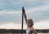 woman in white bikini sitting on pole on water during daytime
