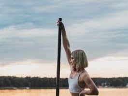 woman in white bikini sitting on pole on water during daytime