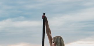 woman in white bikini sitting on pole on water during daytime