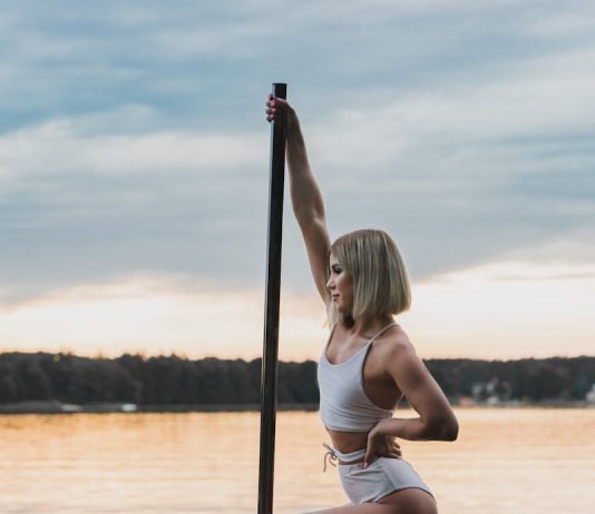 woman in white bikini sitting on pole on water during daytime
