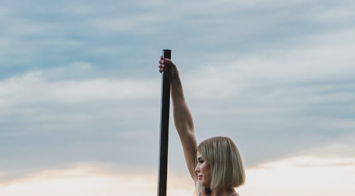 woman in white bikini sitting on pole on water during daytime